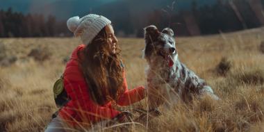 A woman in a field with a dog