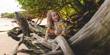 A girl smiling while sitting on a log on a beach